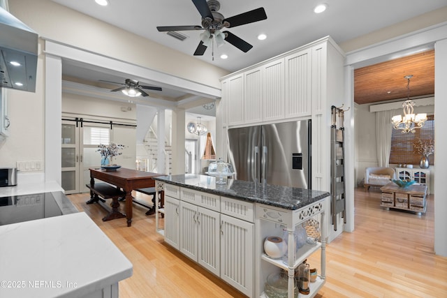 kitchen featuring white cabinetry, stainless steel refrigerator with ice dispenser, light wood finished floors, and a barn door