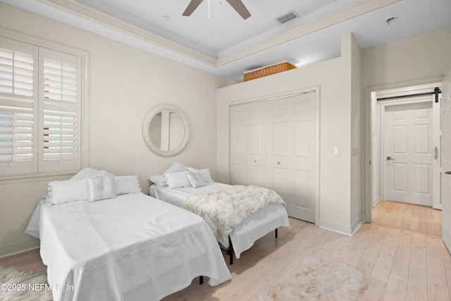 bedroom with light wood finished floors, a closet, visible vents, and baseboards