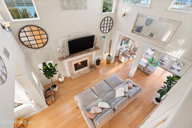 living room with visible vents, a fireplace, wood finished floors, and a towering ceiling