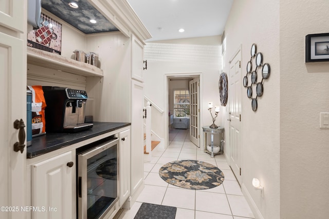 interior space featuring wine cooler, light tile patterned floors, stairway, vaulted ceiling, and a bar