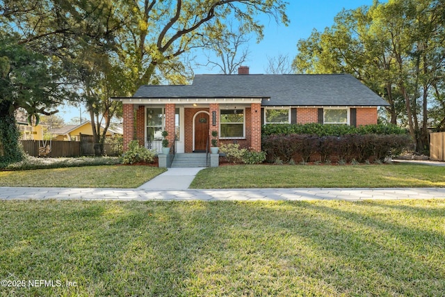 view of front facade featuring a front yard, brick siding, fence, and a chimney