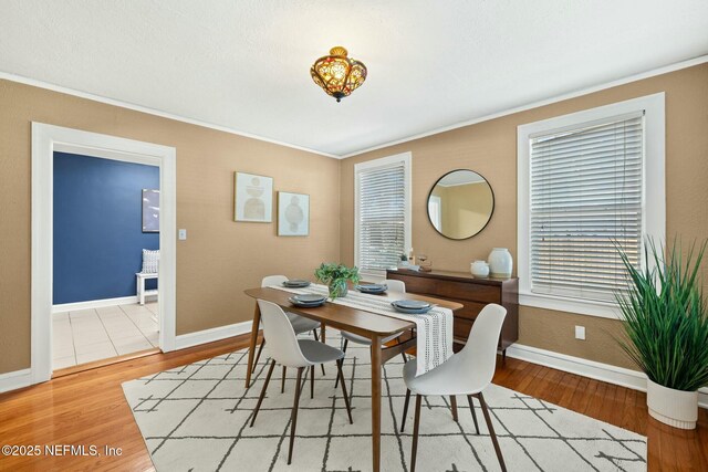 dining space with ornamental molding, baseboards, and wood finished floors