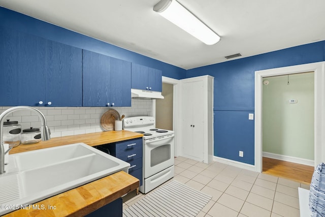 kitchen with under cabinet range hood, a sink, wooden counters, blue cabinetry, and white electric range oven