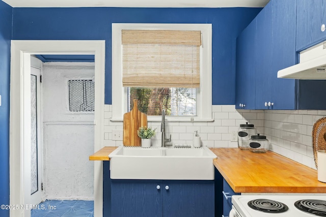 kitchen with backsplash, wooden counters, blue cabinetry, and a sink