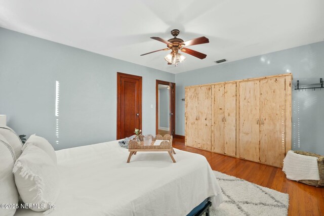 bedroom featuring ceiling fan, visible vents, and wood finished floors