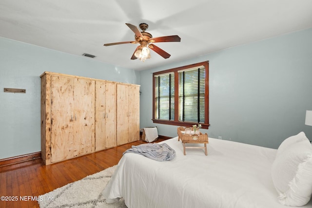 bedroom with ceiling fan, visible vents, and wood finished floors