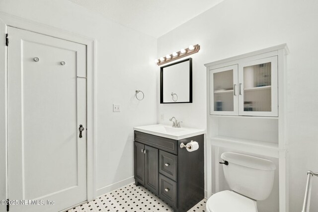 bathroom with toilet, baseboards, and vanity