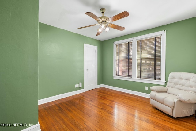 living area featuring ceiling fan, baseboards, and wood finished floors