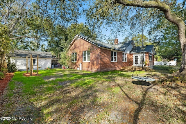 view of side of home featuring a yard, a chimney, french doors, and brick siding