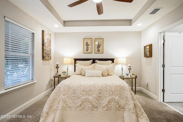 bedroom with carpet flooring, a raised ceiling, and visible vents