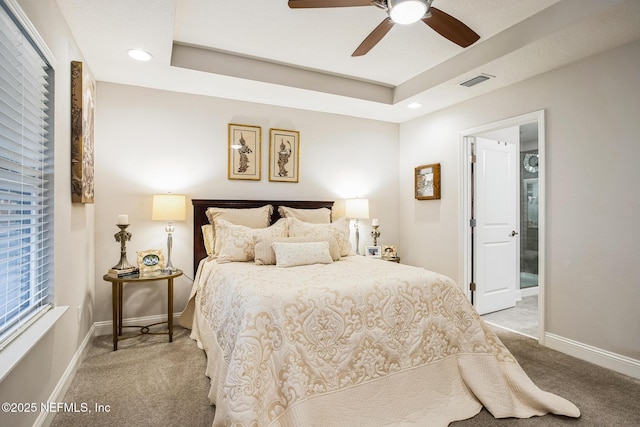 bedroom with light carpet, a tray ceiling, and visible vents