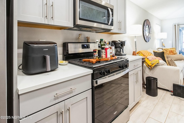 kitchen featuring stainless steel appliances, light countertops, and white cabinetry