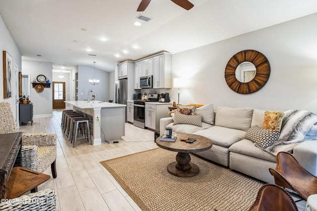 living area featuring lofted ceiling, recessed lighting, visible vents, baseboards, and ceiling fan with notable chandelier