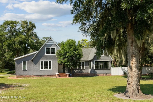 rear view of house with a shingled roof, a lawn, and fence