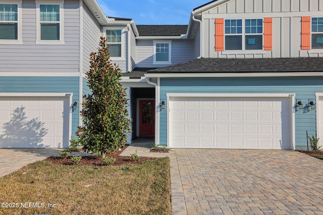 view of front of house with a garage, decorative driveway, board and batten siding, and a front lawn