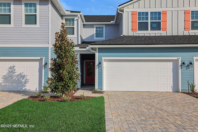 view of front of property featuring decorative driveway, board and batten siding, an attached garage, and a front lawn