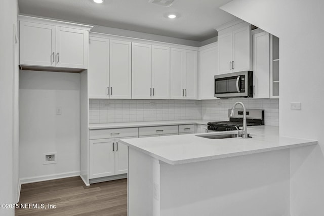 kitchen featuring light wood-type flooring, white cabinetry, stainless steel appliances, and light countertops