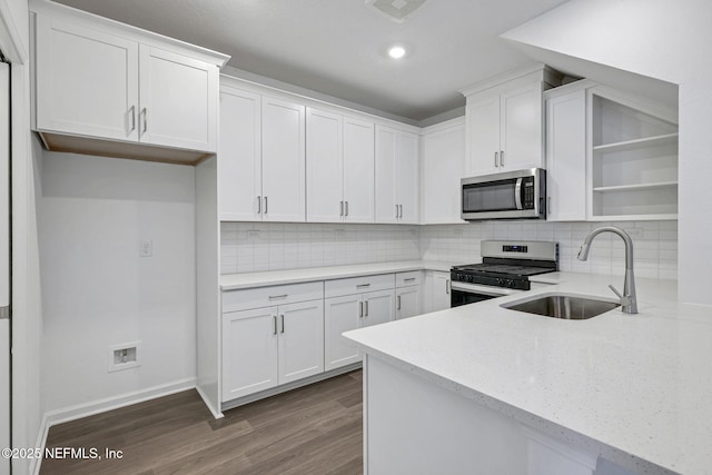 kitchen featuring stainless steel appliances, a sink, white cabinetry, light countertops, and open shelves