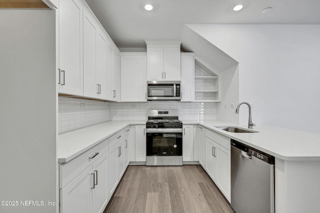 kitchen featuring tasteful backsplash, light countertops, appliances with stainless steel finishes, white cabinets, and a sink