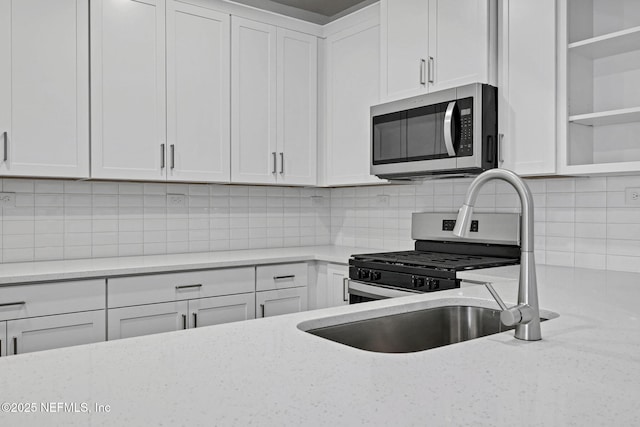 kitchen with decorative backsplash, light stone countertops, stainless steel appliances, white cabinetry, and open shelves