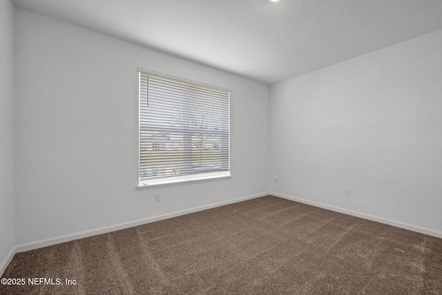 carpeted empty room featuring a textured ceiling and baseboards