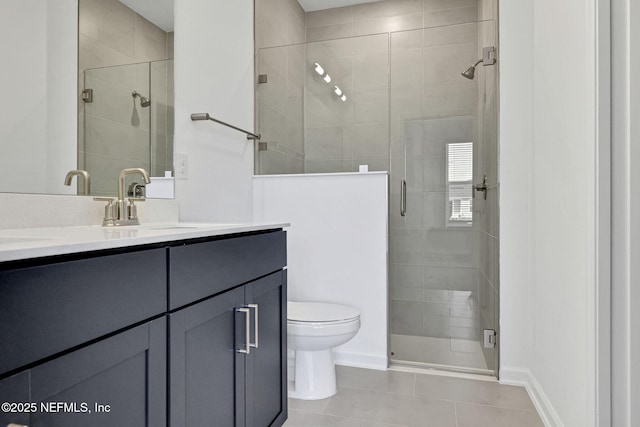 bathroom featuring toilet, a stall shower, vanity, tile patterned flooring, and baseboards