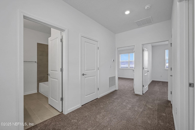 unfurnished bedroom with carpet, visible vents, and baseboards