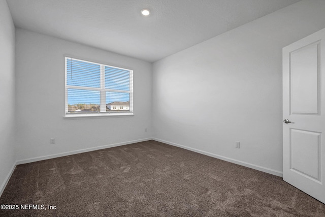 empty room with dark colored carpet and baseboards