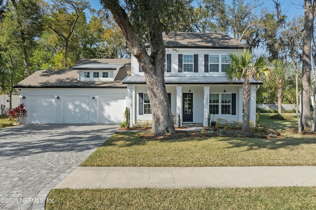 view of front of house with a front lawn, decorative driveway, a porch, and an attached garage