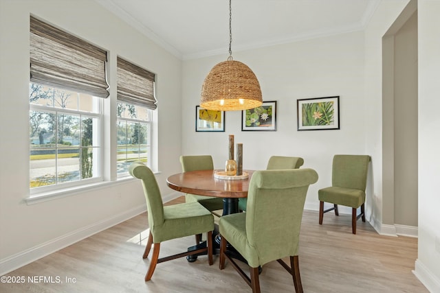 dining room with baseboards, crown molding, and light wood finished floors