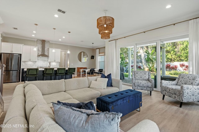 living room featuring light wood finished floors, recessed lighting, visible vents, and crown molding