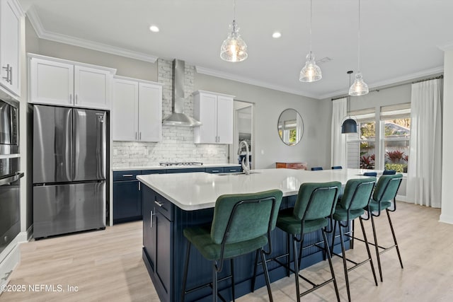 kitchen with stainless steel appliances, wall chimney exhaust hood, light countertops, and crown molding