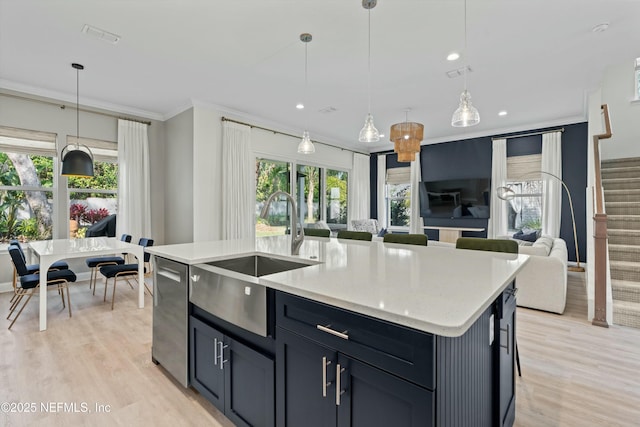 kitchen featuring dishwasher, open floor plan, crown molding, light wood-style floors, and a sink