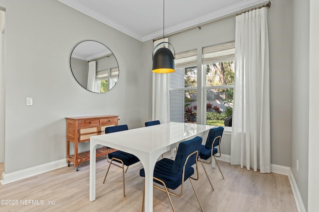 dining space with ornamental molding, light wood-style floors, and baseboards