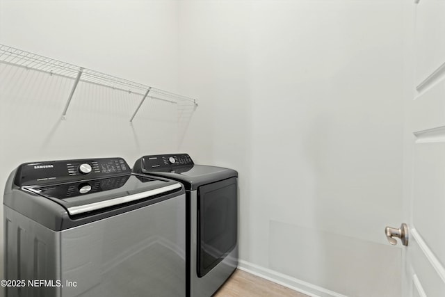 washroom with washing machine and dryer, laundry area, light wood-style flooring, and baseboards