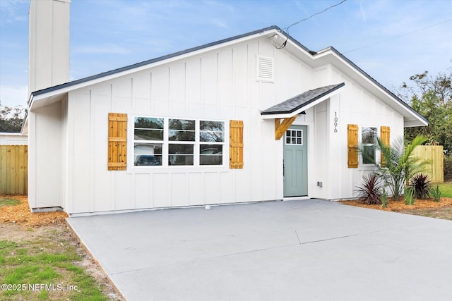 back of property featuring a shingled roof, fence, and board and batten siding