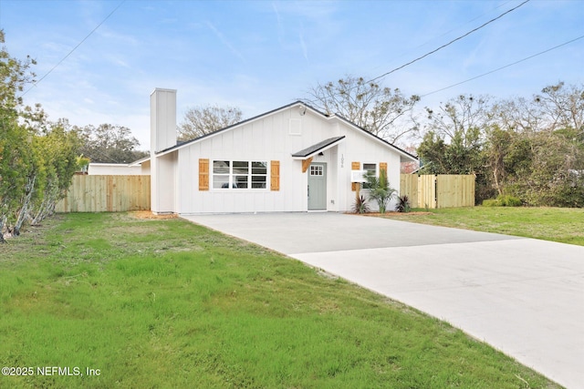 view of front of property with fence, board and batten siding, and a front yard