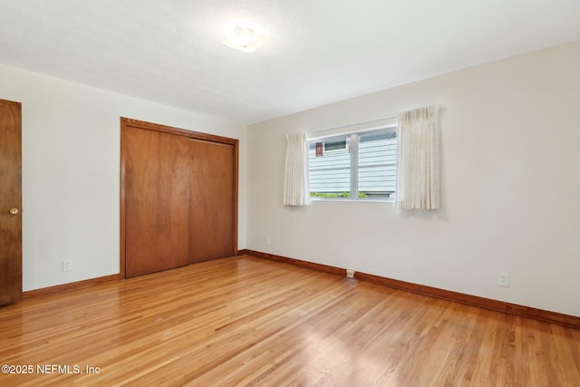 unfurnished bedroom with a closet, baseboards, and light wood finished floors