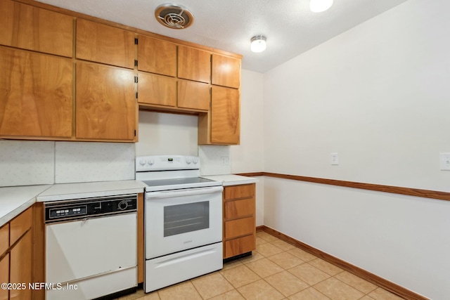 kitchen featuring light tile patterned floors, light countertops, visible vents, white appliances, and baseboards