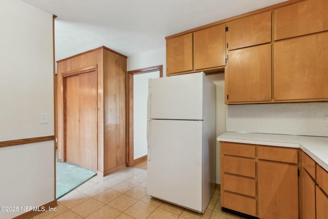 kitchen featuring freestanding refrigerator, light countertops, baseboards, and light tile patterned flooring