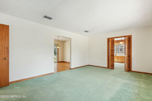 spare room with carpet, visible vents, a notable chandelier, and baseboards