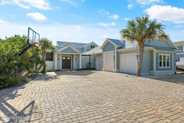 view of front of home with metal roof, decorative driveway, a standing seam roof, and an attached garage