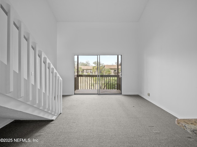 interior space with carpet floors, a towering ceiling, and baseboards