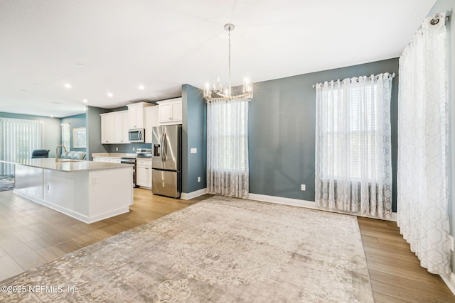 427 Ladyslipper Dr, Saint Johns, FL 32259 - kitchen with a sink, a chandelier, stainless steel appliances, white cabinets, and light wood-style floors