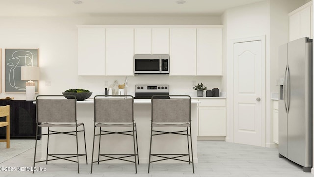 kitchen with stainless steel appliances, white cabinetry, an island with sink, and a kitchen bar