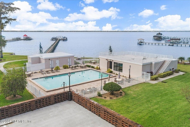 pool featuring a yard, a patio, a water view, and fence