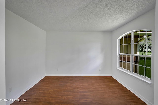 spare room featuring baseboards, dark wood-style flooring, a textured ceiling, and a healthy amount of sunlight