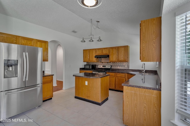 kitchen featuring a center island, pendant lighting, arched walkways, stainless steel appliances, and a sink