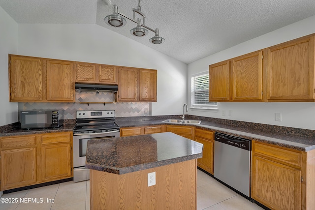 kitchen featuring stainless steel appliances, a center island, under cabinet range hood, and dark countertops