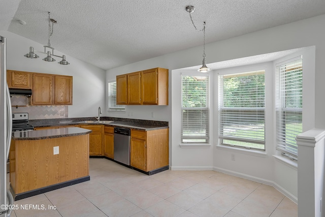 kitchen with a sink, vaulted ceiling, hanging light fixtures, appliances with stainless steel finishes, and dark countertops